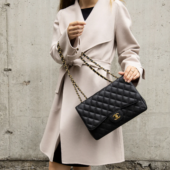 woman carrying a chanel flap handbag in black.